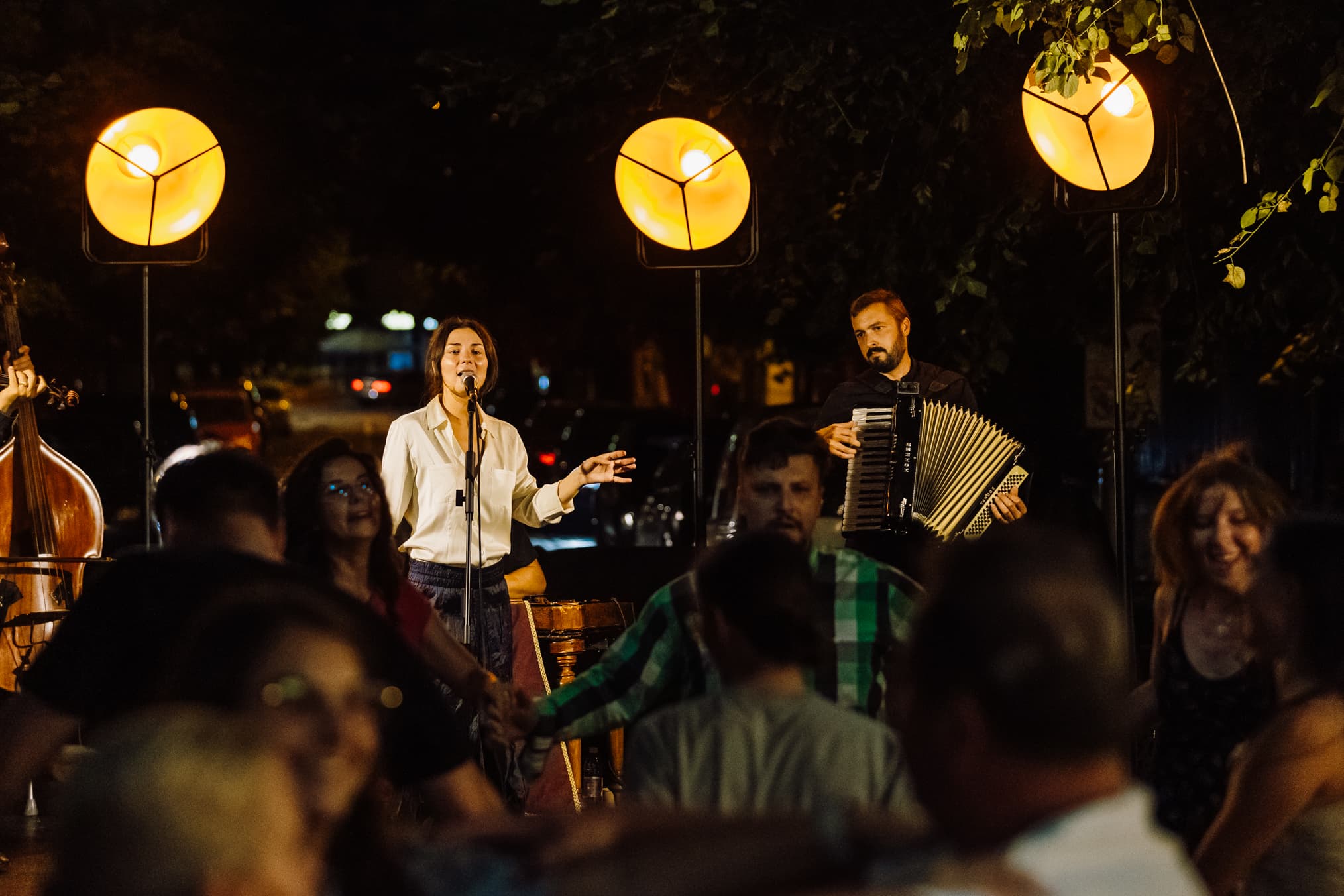 Public la un concert de seară, sub beculețe